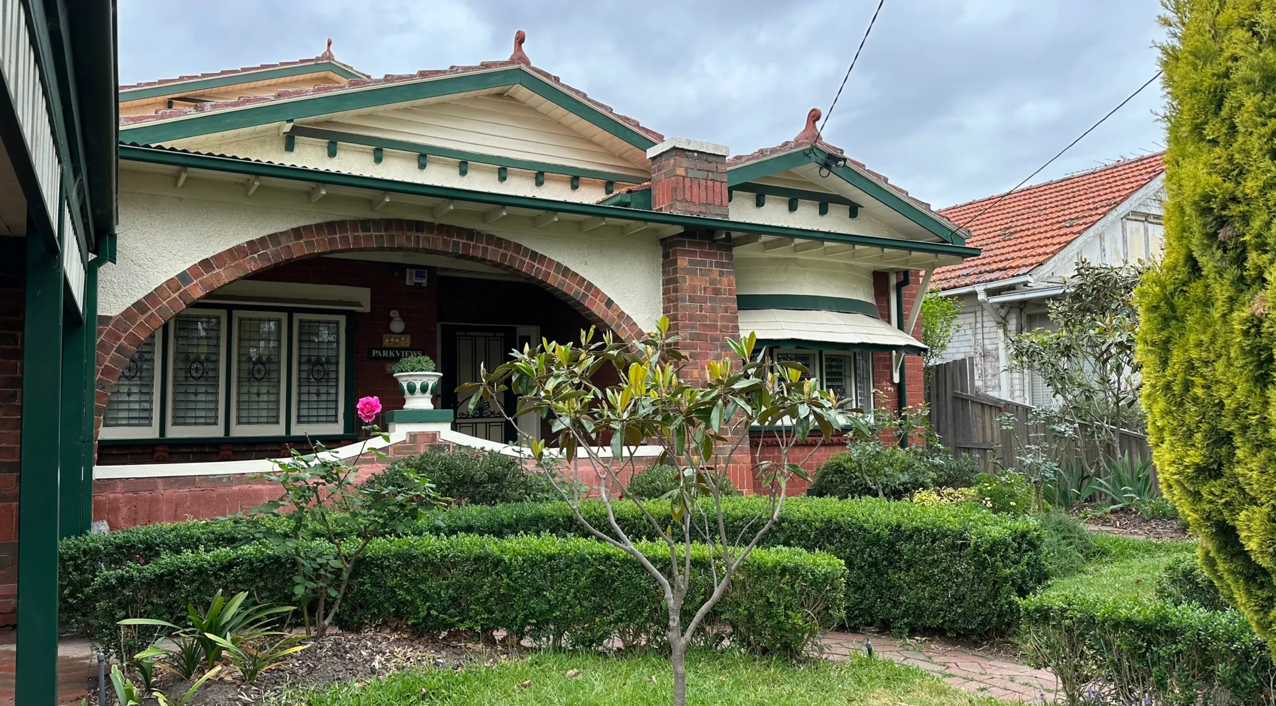 Brick house with arched porch, subsidence signs and wall cracks visible.